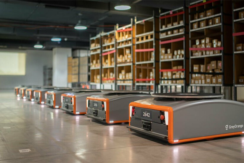Image showing warehouse robots aligned in rows with shelves in the background associated with GreyOrange